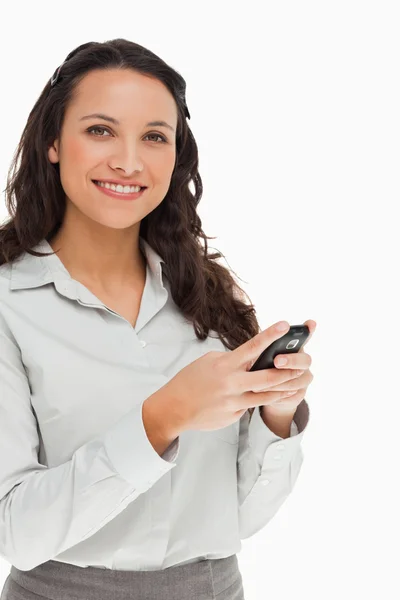 Portret brunetka uśmiechający się podczas korzystania z telefonu komórkowego — Zdjęcie stockowe