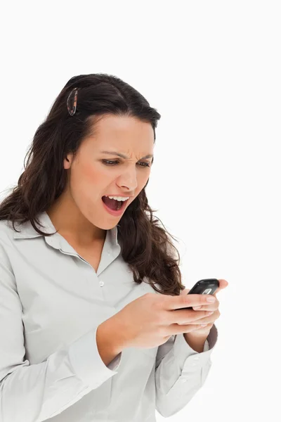 Brunette fronsen tijdens het gebruik van haar mobiele — Stockfoto