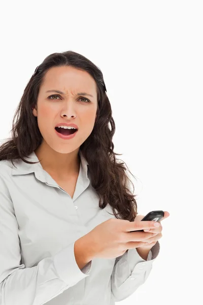 Porträtt av en brunett som rynkar pannan medan du använder sin mobil — Stockfoto