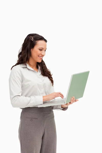 Brunette staande tijdens het gebruik van een laptop — Stockfoto