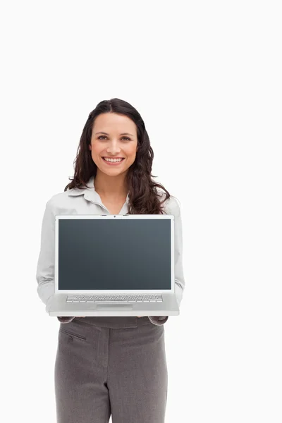 Lachende brunette staande terwijl een laptop scherm wordt weergegeven — Stockfoto
