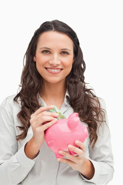 Brunette geld steken in de piggy bank — Stockfoto