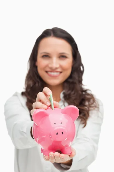 Portrait of a brunette putting money in the piggy bank — Stock Photo, Image
