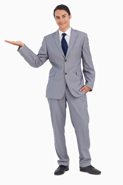 Hombre sonriente en traje presentando con la mano — Foto de Stock