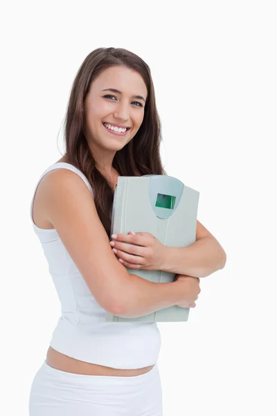Smiling young woman holding a weighing scales — Stock Photo, Image