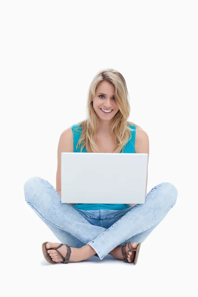 一个年轻女子正坐在地上用一台笔记本电脑 — 图库照片