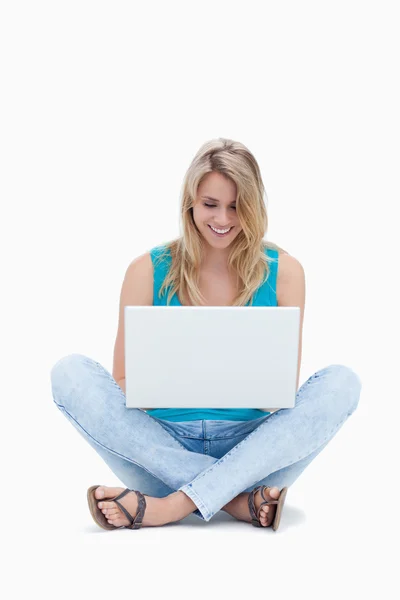 Une femme est assise sur le sol regardant son ordinateur portable — Photo