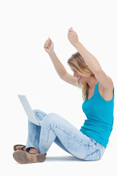 Kobieta ma ręce w powietrzu i laptopa między jej nogi — Zdjęcie stockowe