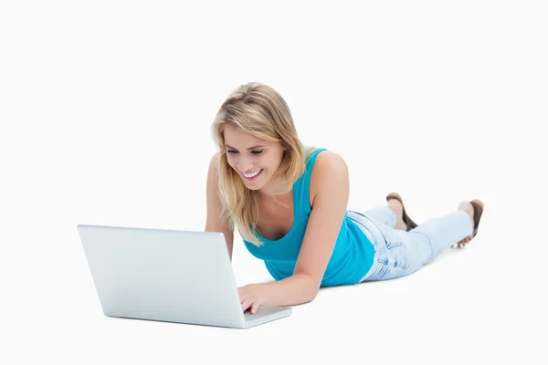 Una giovane donna sdraiata sul pavimento con un computer portatile — Foto Stock