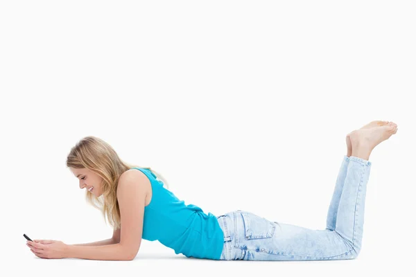 Kobieta leży na podłodze z nogami odbyło się jest SMS-y na jej — Zdjęcie stockowe