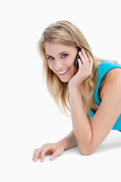 A smiling woman looking at the camera is talking on her mobile p — Stock Photo, Image