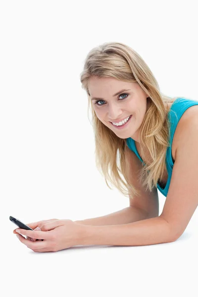 Uma mulher segurando um telefone celular está sorrindo para a câmera — Fotografia de Stock