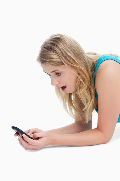 Een verbaasd jonge vrouw is op zoek op haar mobiele telefoon — Stockfoto