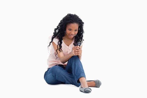 Zaskoczony kobieta siedzi na podłodze jest SMS-y od jej telefon — Zdjęcie stockowe