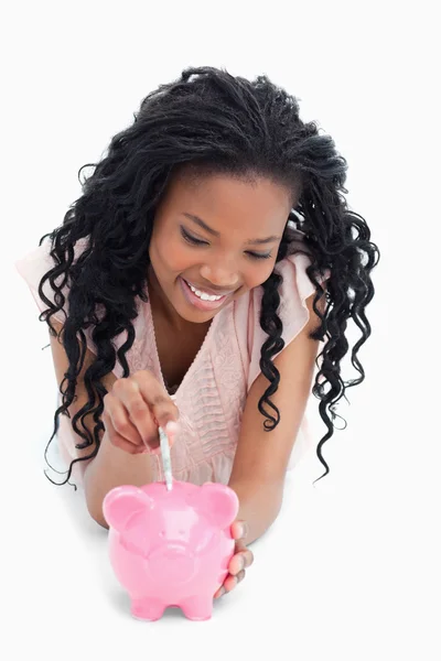 Een jong meisje liggend op de vloer geld steken in een piggy bank — Stockfoto