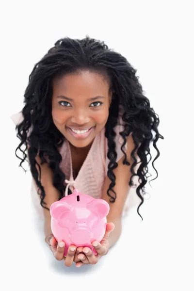 Egy fiatal nő mosolyogva a kamerát tartja a piggy bank h — Stock Fotó