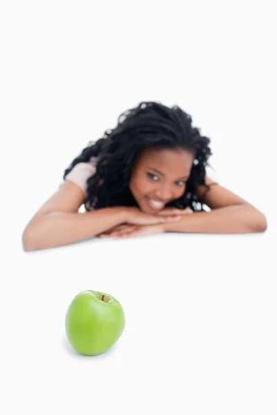 A green apple with a smiling girl in the background — Stock Photo, Image