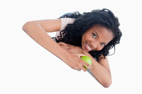 En ung flicka som ligger på marken håller ett äpple — Stockfoto