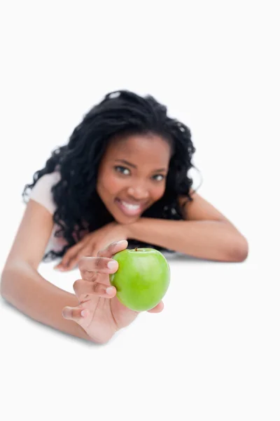 Een jong meisje is een groene appel stak voor haar — Stockfoto