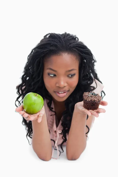Ein Apfel und ein Brötchen werden auf den Handflächen einer jungen Frau hochgehalten. — Stockfoto