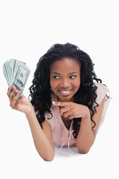 Una mujer sonriente señala dólares americanos en su mano — Foto de Stock