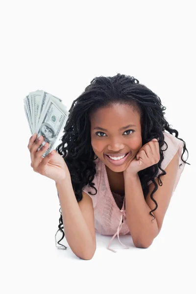 En kvinna som vilar sitt huvud på hennes hand håller americn dollar — Stockfoto