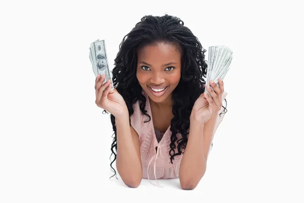 Una mujer joven sostiene dólares americanos y sonríe a la cámara — Foto de Stock