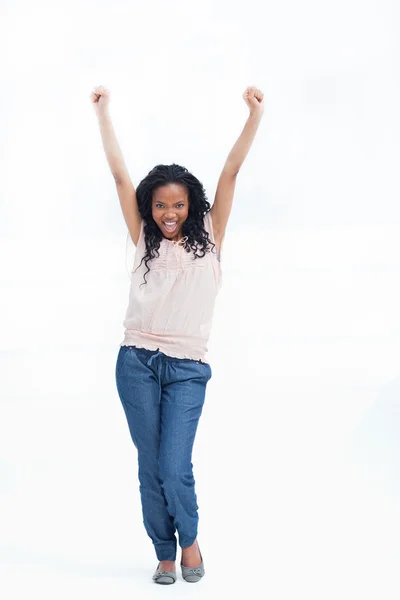 Eine junge lachende Frau steht mit erhobenen Armen in der Luft — Stockfoto