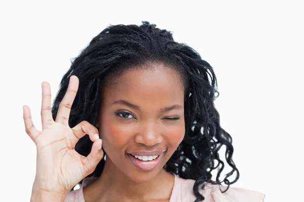 A young woman winking and holding her hand in the okey sign — Stock Photo, Image