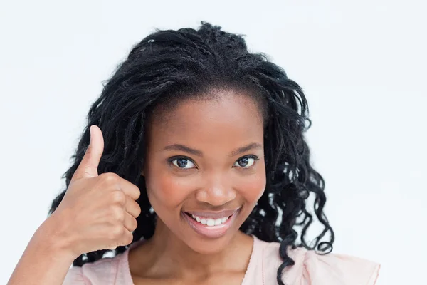 Uma jovem mulher sorrindo para a câmera com o polegar para cima — Fotografia de Stock