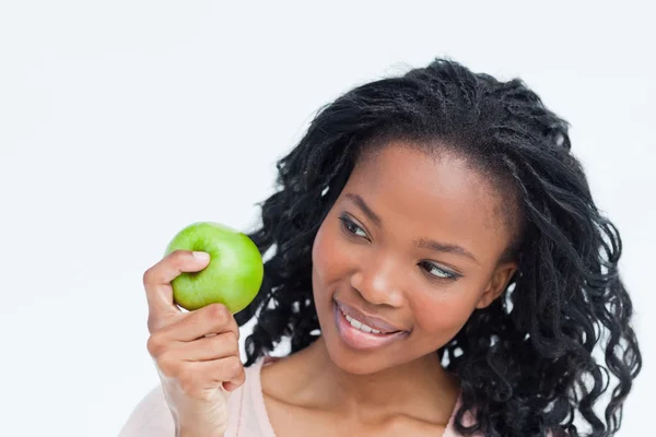 Eine Frau blickt auf einen Apfel, den sie in der Hand hält — Stockfoto