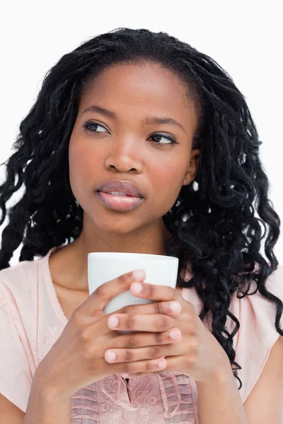 Una giovane donna che tiene una tazza con entrambe le mani — Foto Stock