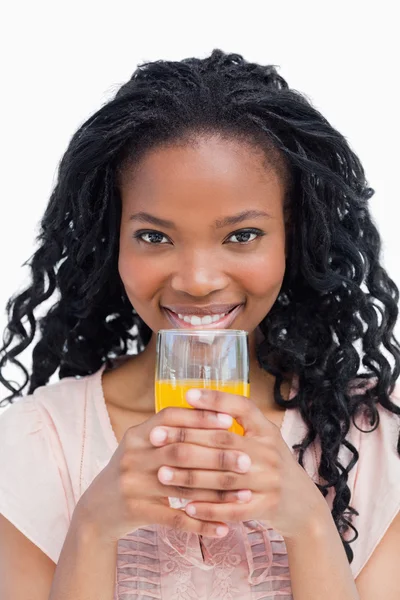 Młoda kobieta trzymając szklankę soku pomarańczowego z jej strony — Zdjęcie stockowe