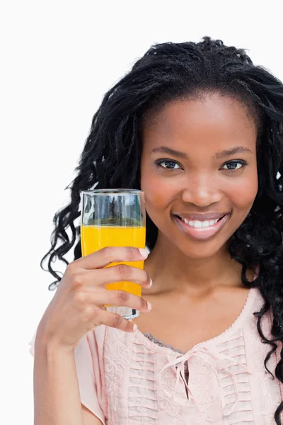 Acercamiento de una joven sonriente sosteniendo un vaso en juic naranja — Foto de Stock