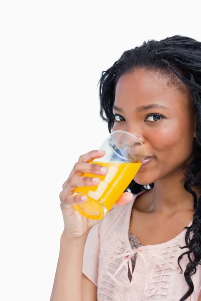 一个女孩看相机喝橙汁 — 图库照片