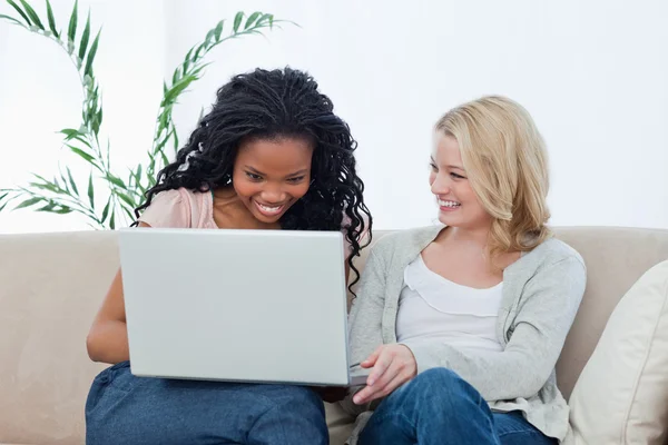 Duas mulheres com um laptop na frente delas estão rindo — Fotografia de Stock