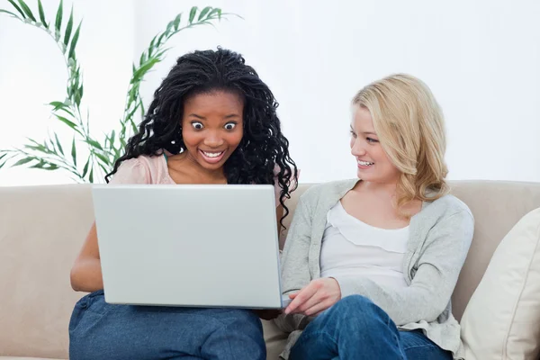 Uma mulher surpresa olhando para um laptop com seu amigo — Fotografia de Stock