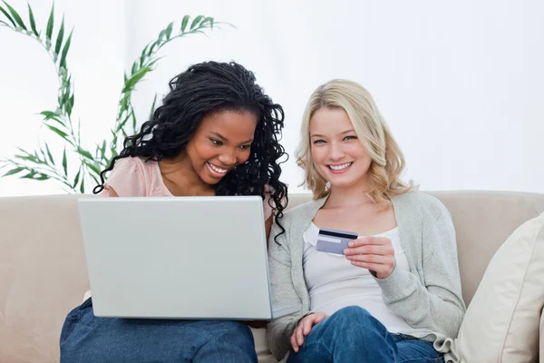 En kvinna med ett bankkort sitter med sin kompis som har en — Stockfoto