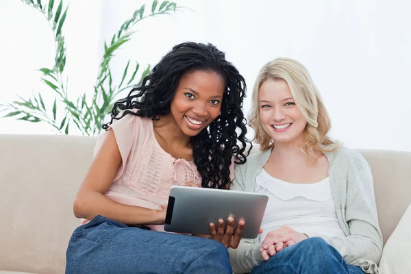 Δύο γυναίκες να χαμογελά στη φωτογραφική μηχανή με έναν υπολογιστή δισκίο, μπροστά — Φωτογραφία Αρχείου