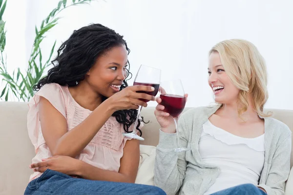 Dvě ženy držící sklenice na víno se usmívají na sebe — Stock fotografie