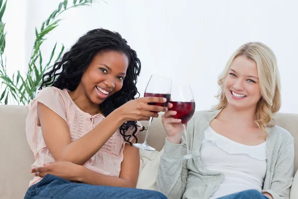 Dwie kobiety gospodarstwa kieliszki do wina są uśmiechając się do kamery — Zdjęcie stockowe