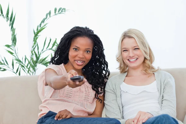 Uma mulher com seu amigo está apontando um controle remoto de televisão — Fotografia de Stock