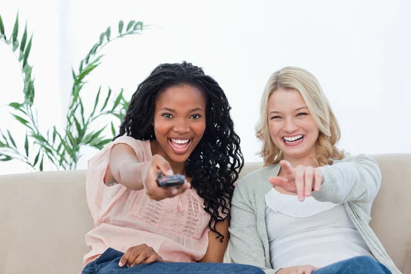 A woman pointing a television remote control at the camera with — Stock Photo, Image