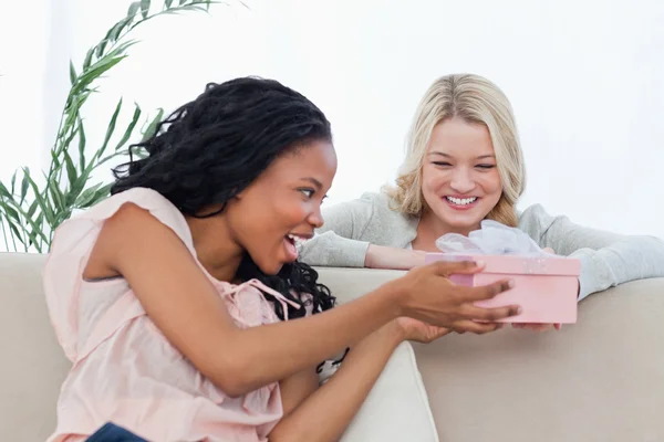 Uma mulher dando um presente em uma caixa para seu amigo — Fotografia de Stock