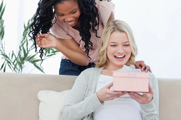 En förvånad kvinna håller en present med sin vän ständiga — Stockfoto