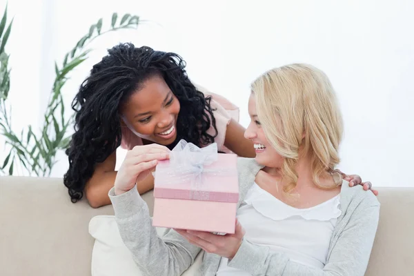 Een vrouw met een geschenk is glimlachend op haar vriend — Stockfoto