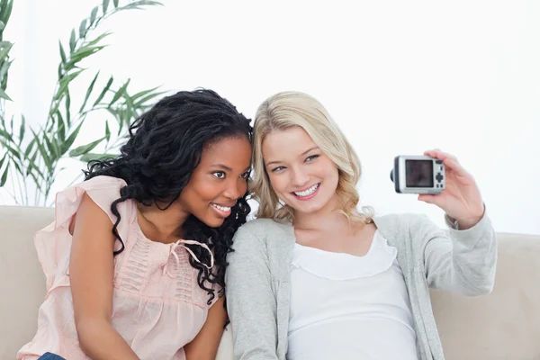 Dos mujeres están sentadas tomando fotos de sí mismas con una cámara — Foto de Stock