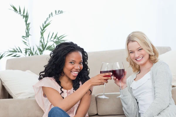 Dwie kobiety, siedząc na podłodze, trzymając kieliszki do wina — Zdjęcie stockowe