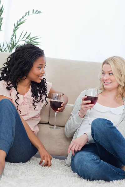Dwie kobiety siedzącej przed kanapą jest Picie wina — Zdjęcie stockowe