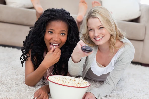 Zwei Frauen liegen mit einer Schüssel Popcorn auf dem Boden — Stockfoto